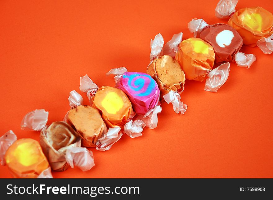 Colorful wrapped taffy candy on orange background