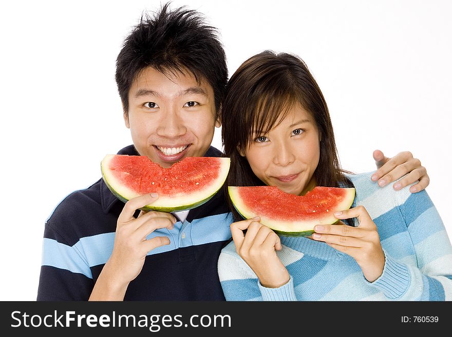 A young asian couple eating watermelon. A young asian couple eating watermelon