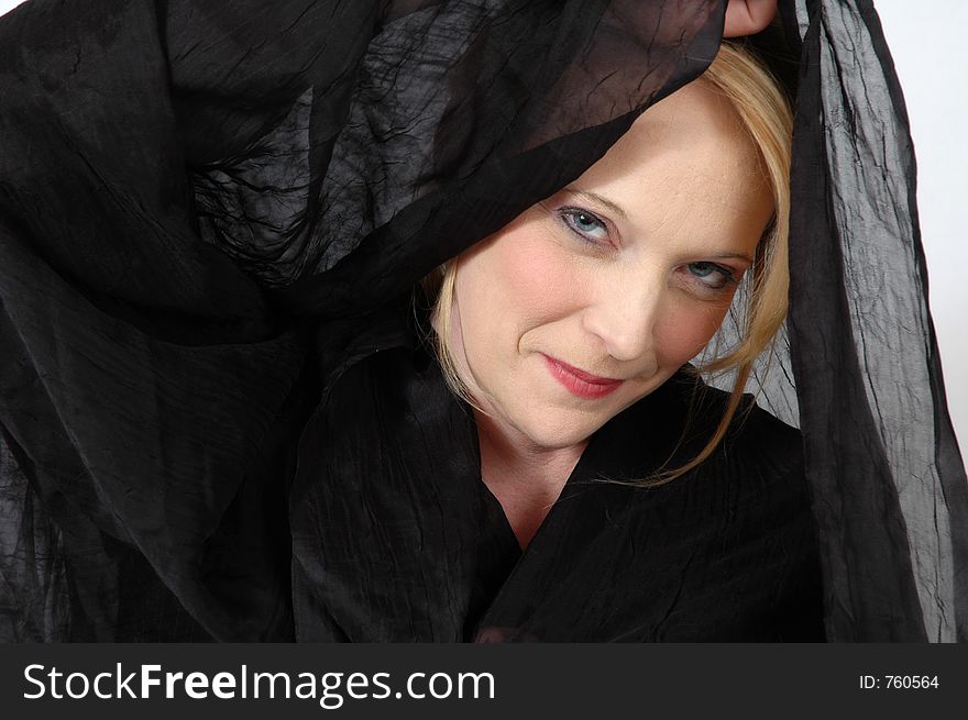 Blond woman drapped under black material. You can only see her face. Blond woman drapped under black material. You can only see her face.