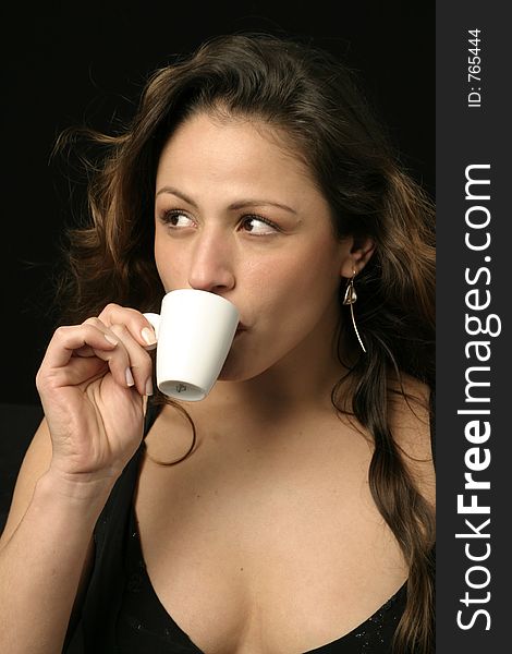 Beautiful brunette Brazilian woman sips a cup of hot chocolate or coffee. Beautiful brunette Brazilian woman sips a cup of hot chocolate or coffee