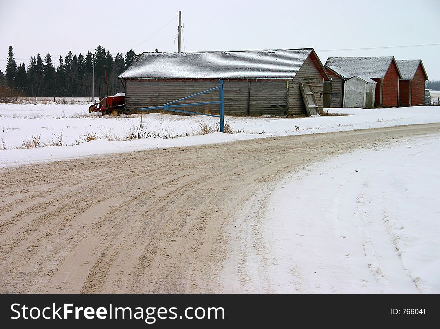 Weathered farm buildings along side a dirty road of snow. Weathered farm buildings along side a dirty road of snow