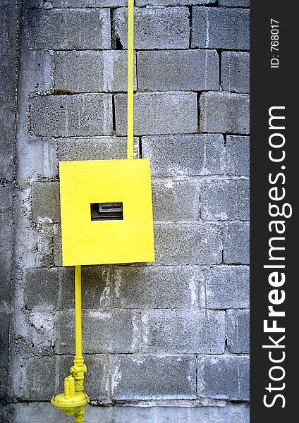 Yellow gas counter contrasting with the cement bricks wall on which it is installed. 35mm film scan