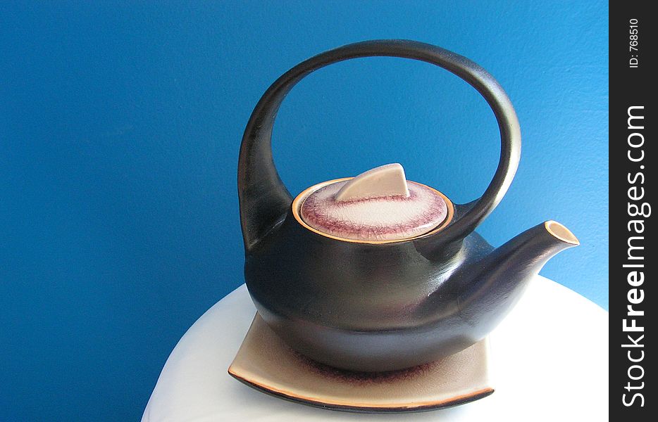 Asian teapot isolated against blue wall