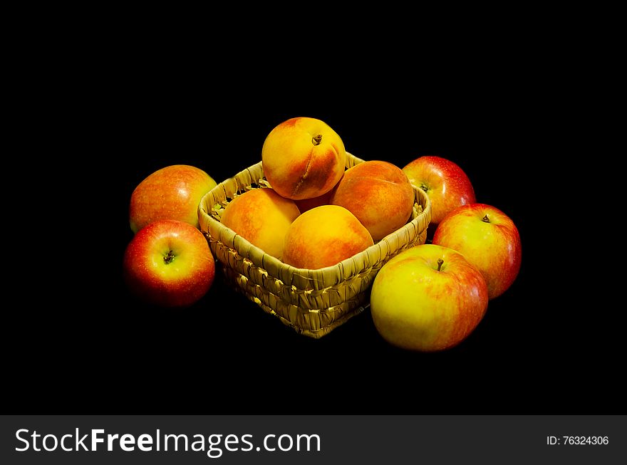 Summer peach ripe fruit in a wicker bowl with red apples on a dark background. Summer peach ripe fruit in a wicker bowl with red apples on a dark background
