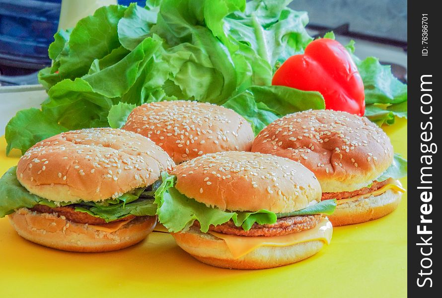 Picture with delicious beef hamburger with salad and cheese on a yellow plate. Picture with delicious beef hamburger with salad and cheese on a yellow plate