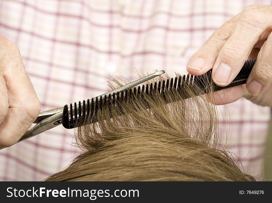 Light brown hair trimmed on black comb with silver scissors. Light brown hair trimmed on black comb with silver scissors