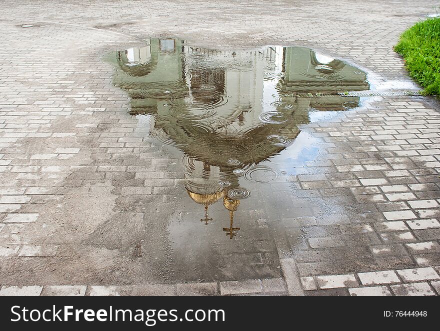 White church reflected in a puddle in the rain closeup