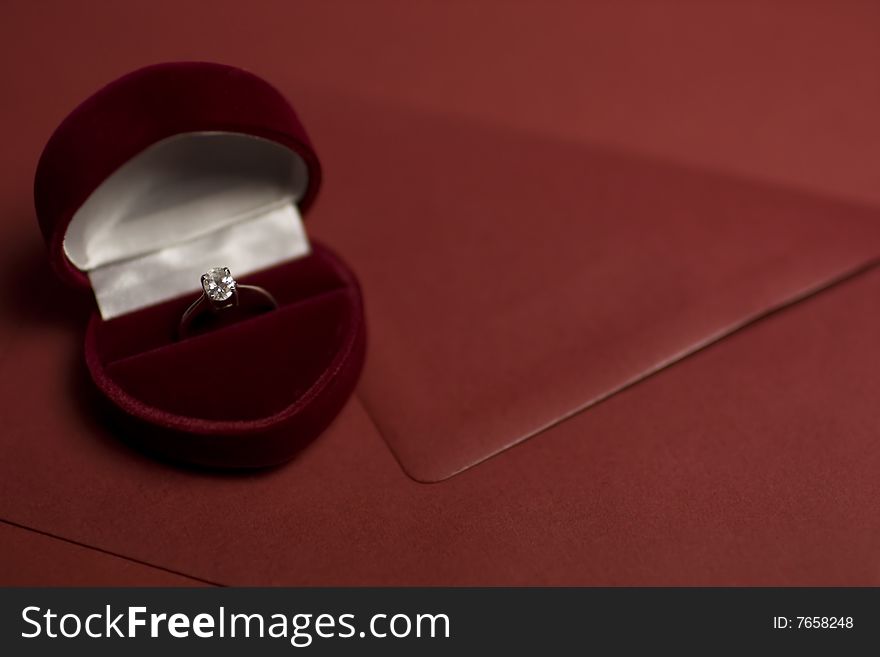 A diamond ring in a deep purple velvet box shaped as a heart lying on an envelope. A diamond ring in a deep purple velvet box shaped as a heart lying on an envelope.