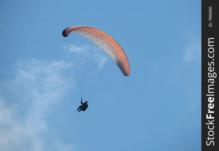 Parachutist which flies in the blue sky