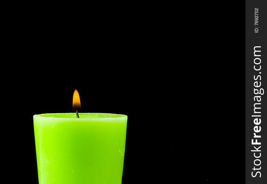 Green burning candle on a dark background with apple aroma