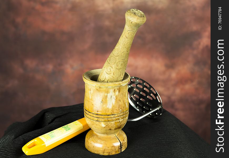 Mortar and pestle with potato masher on a black ground. Mortar and pestle with potato masher on a black ground.