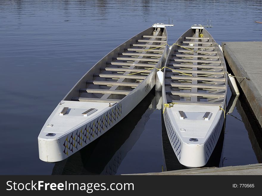 Two Dragon boats tied to a dock.