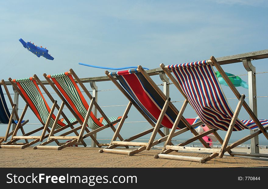 Beach chairs near the coastline. A kite on the background