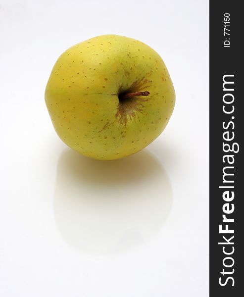 Yellow green apple on reflective surface