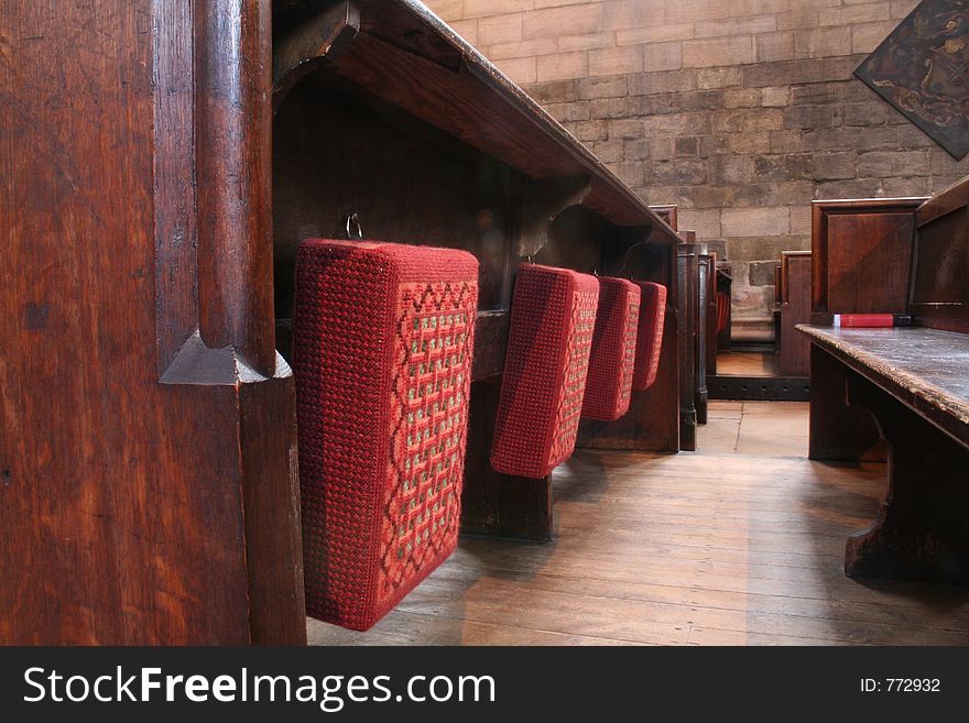 Beautiful tapestry prayer cushions hang on back of pew