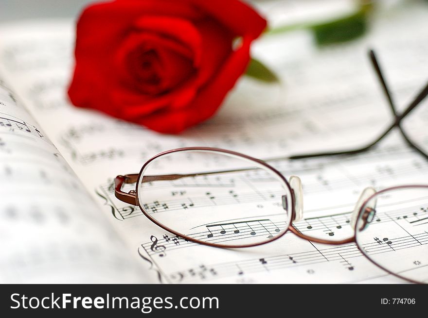 Close up of music sheet, eye glasses, and rose. romance concept. Close up of music sheet, eye glasses, and rose. romance concept.