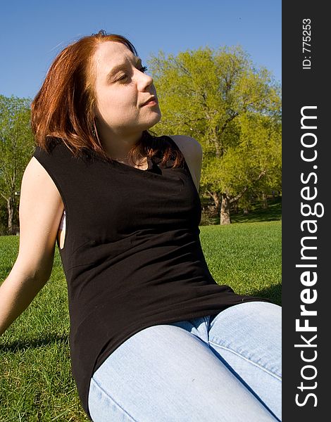 An attractive young lady gazes onward during a warm, summer day in the park. An attractive young lady gazes onward during a warm, summer day in the park.