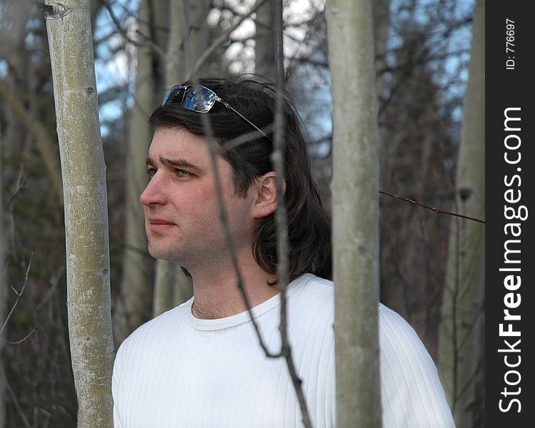 Man standing in midle of forest , in white shirt and sunglasses on his head. Man standing in midle of forest , in white shirt and sunglasses on his head