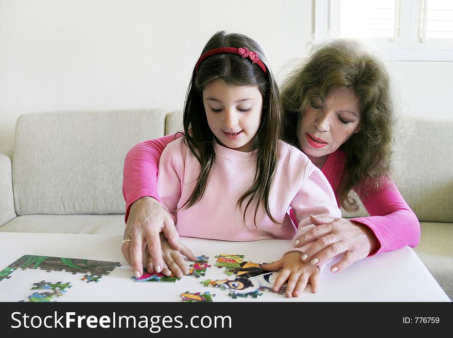 Loving mother helps her little daughter solve a puzzle. Loving mother helps her little daughter solve a puzzle