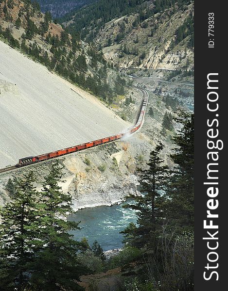 Freight train going through mountain area and near river. BC area