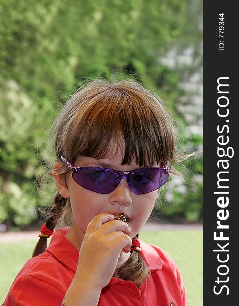 Child with blue sunglasses, eating sweet date