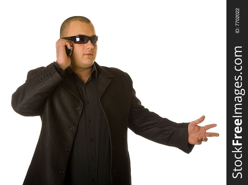 Man in black suit in sun glasses talking on the mobile phone. Isolated on white background