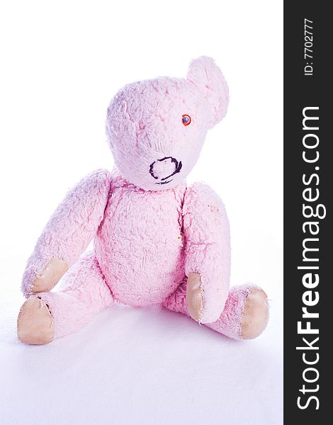 Old and worn pink teddy bear isolated on white