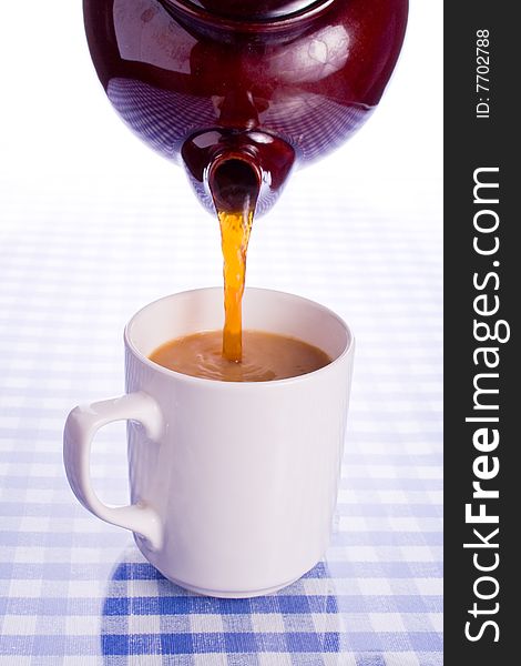 Tea being poured into a large cup on a refective surface. Tea being poured into a large cup on a refective surface