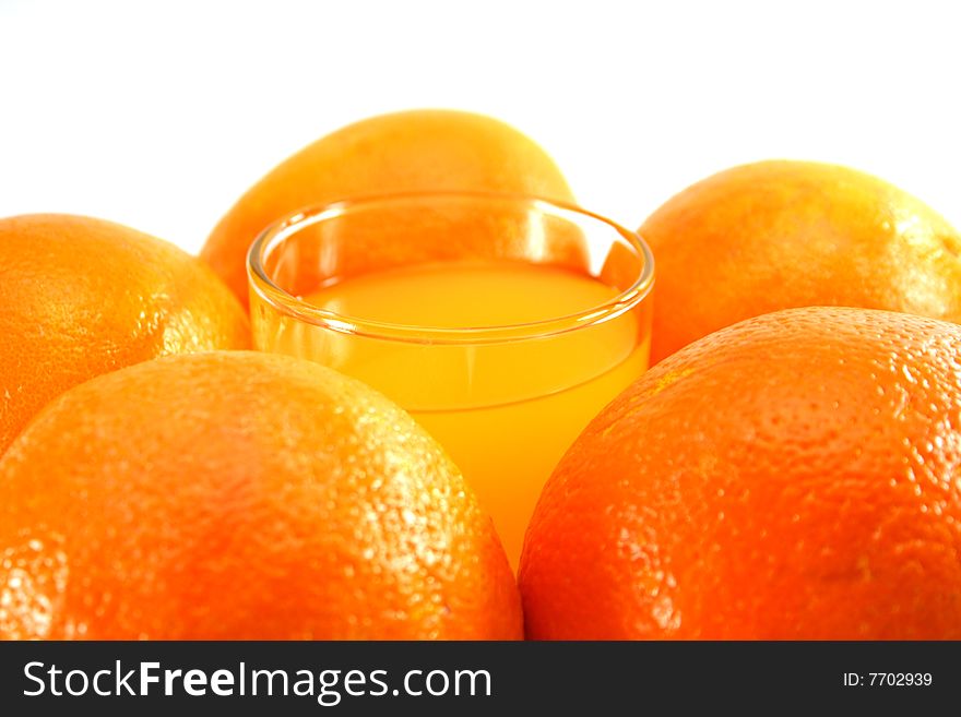 Orange juice in a glass and oranges on a white background