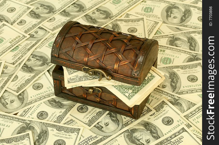 Wooden chest with dollars costs on dollars background
