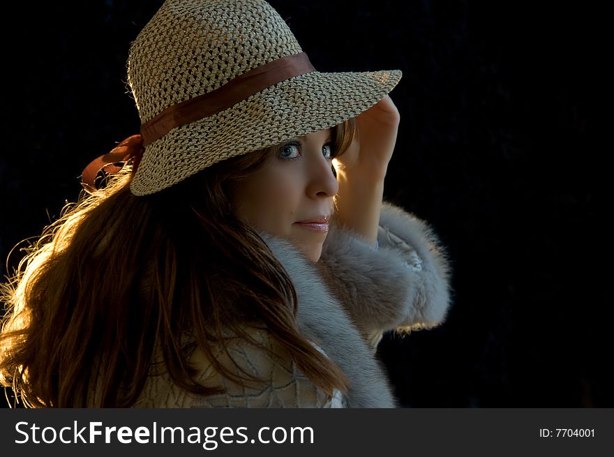 Young lady tryimg on a hat, on a black background