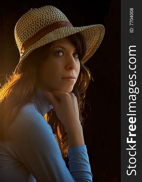 Young lady with straw hat on, on black background