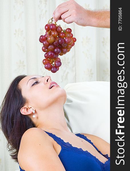 Close up portrait of nice young brunette getting tempted with grape. Close up portrait of nice young brunette getting tempted with grape