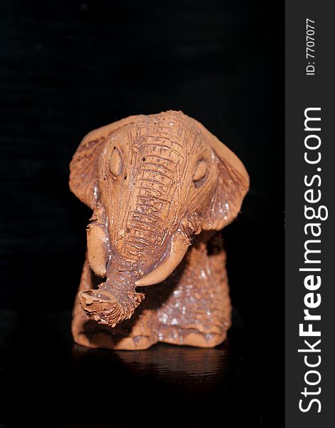 Brown clay elephant on a black background