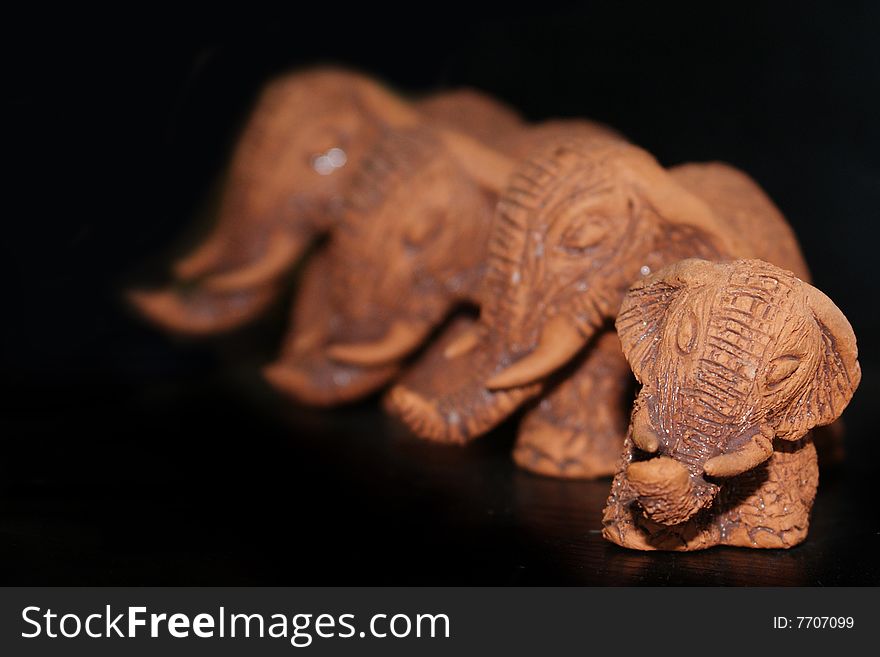 4 Brown clay elephants on a black background