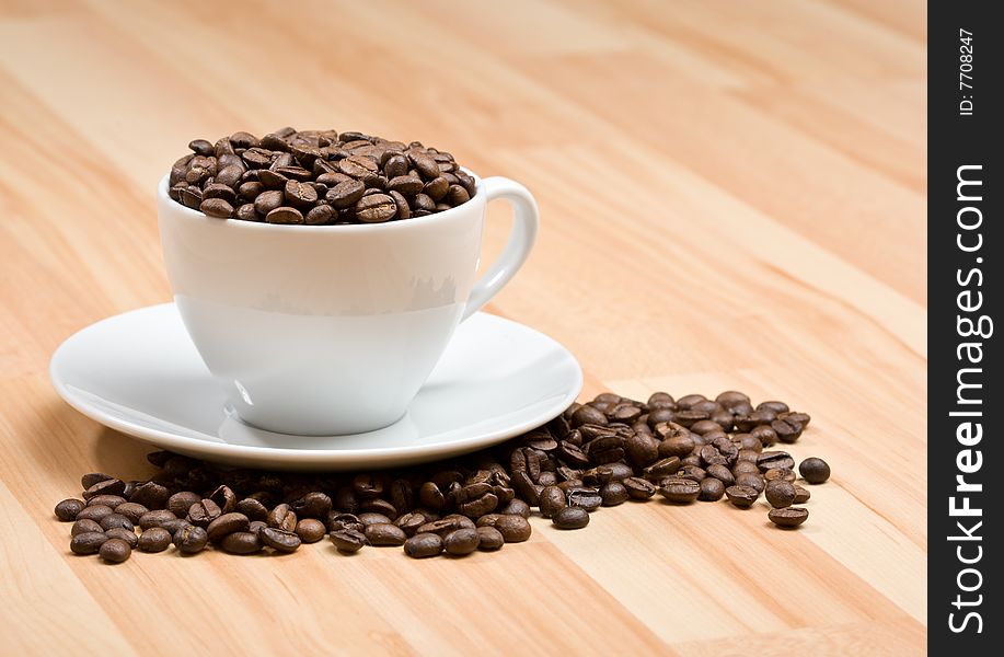 Cup with freshly roasted coffee beans on hardwood floor or on the table. Cup with freshly roasted coffee beans on hardwood floor or on the table