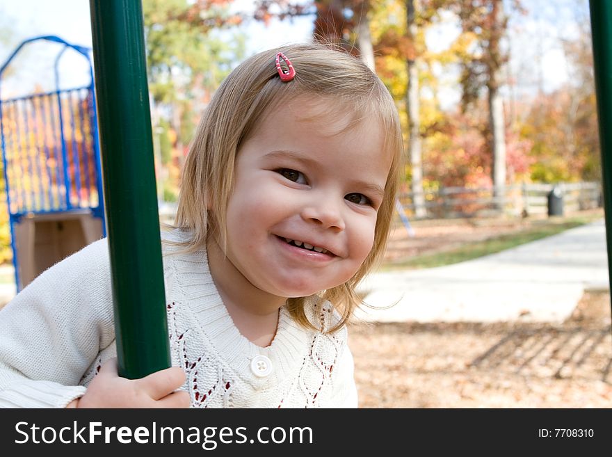 A little girl on the playground on an autumn day