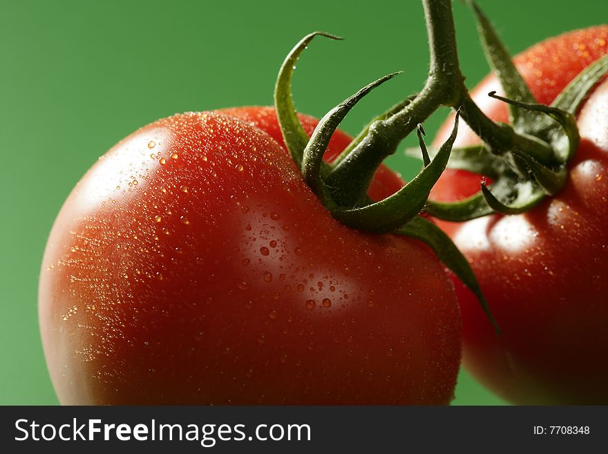 Red wet tomato macro over green background at studio. Red wet tomato macro over green background at studio