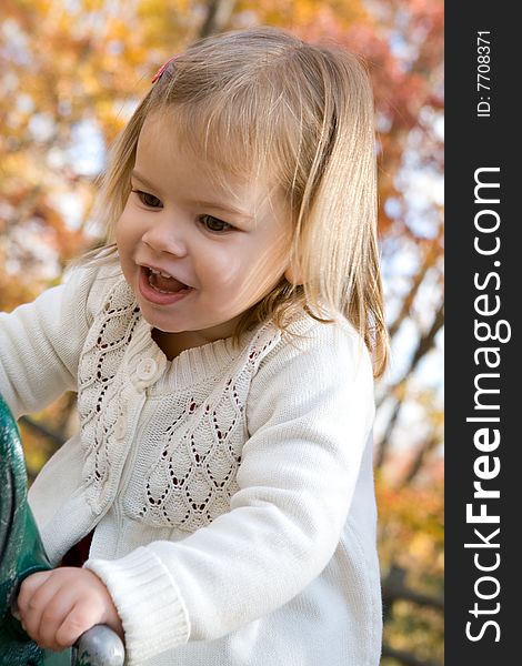 A little girl on the playground on an autumn day