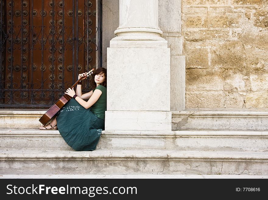 Young female guitarist beggind at the church entrance. Young female guitarist beggind at the church entrance