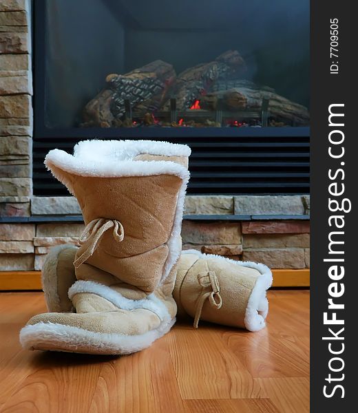 A pair of fuzzy boot style slippers tossed by the fireplace. A pair of fuzzy boot style slippers tossed by the fireplace.