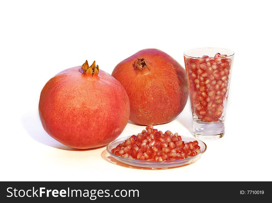 Pomegranates on white background with seeds in  glass and on the plate. Pomegranates on white background with seeds in  glass and on the plate