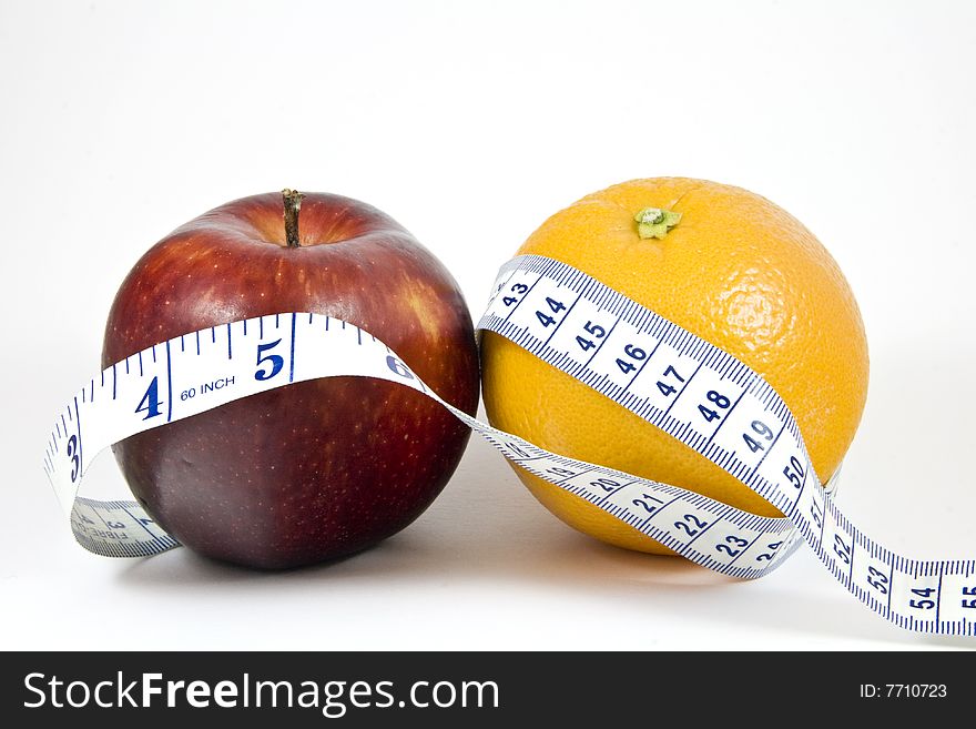 An apple and orange wrapped by a tape measure; isolated on white. An apple and orange wrapped by a tape measure; isolated on white