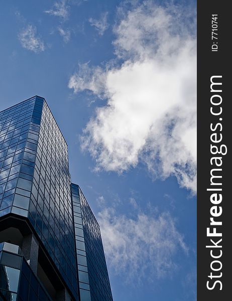 An overhead shot of a single skyscraper with clouds having a bluish tint