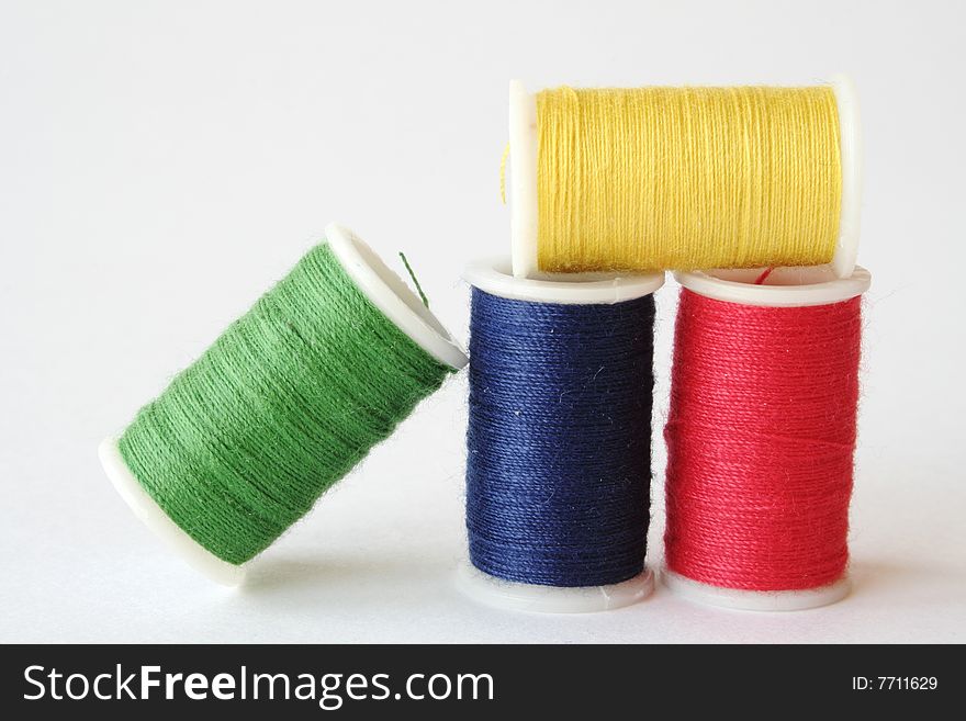 Four spools of thread, each a primary color, on a white background. Four spools of thread, each a primary color, on a white background