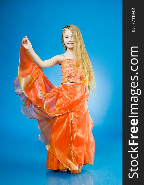 Smiling little girl in orange dress over blue background
