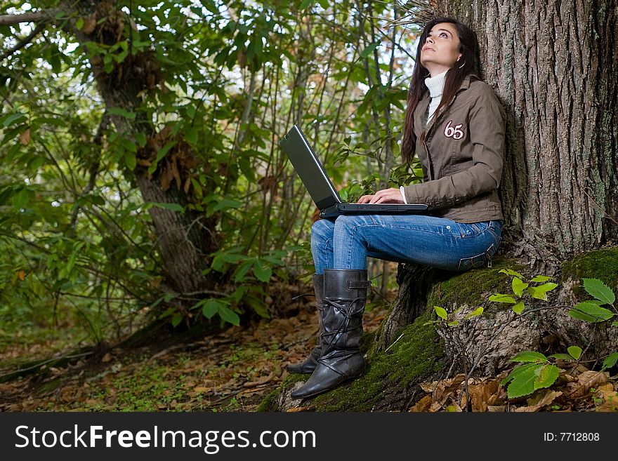 Young woman working with laptop on deep forest