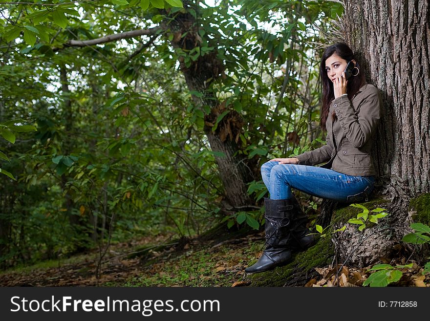 Young woman talking by phone on deep forest. Young woman talking by phone on deep forest