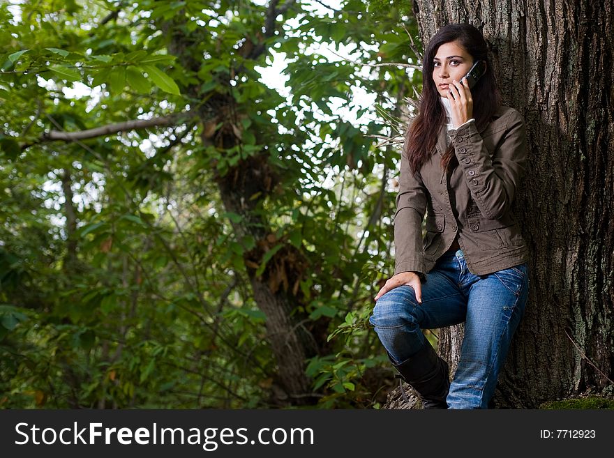 Young woman talking by phone on deep forest great space for copy. Young woman talking by phone on deep forest great space for copy