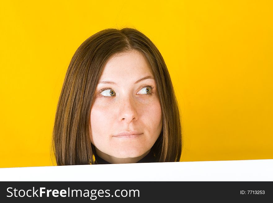 Beautiful woman looking into the right corner. On yellow background